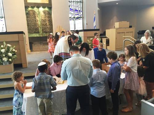 Rabbi Miller and students gather around a table in the Sanctuary
